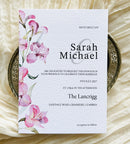 Wedding invitation card with pink lily floral design on a textured surface
