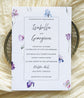 Wedding invitation card with blue, pink and purple floral design on a textured surface
